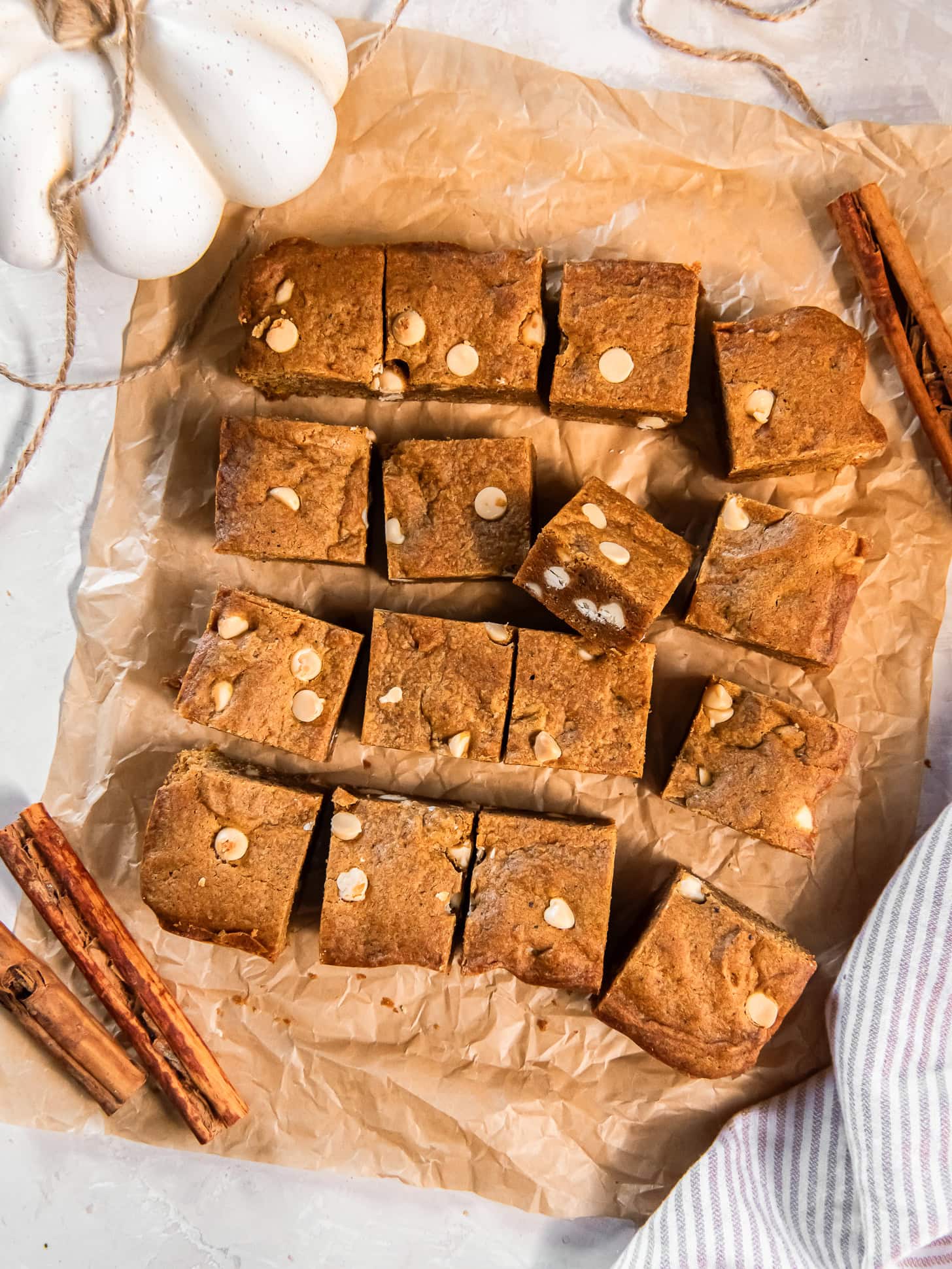 Pumpkin blondies cut into small squares on parchment paper.