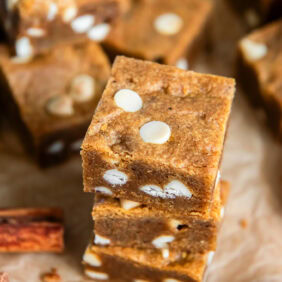 Stacked pumpkin blondies with white chocolate chips.