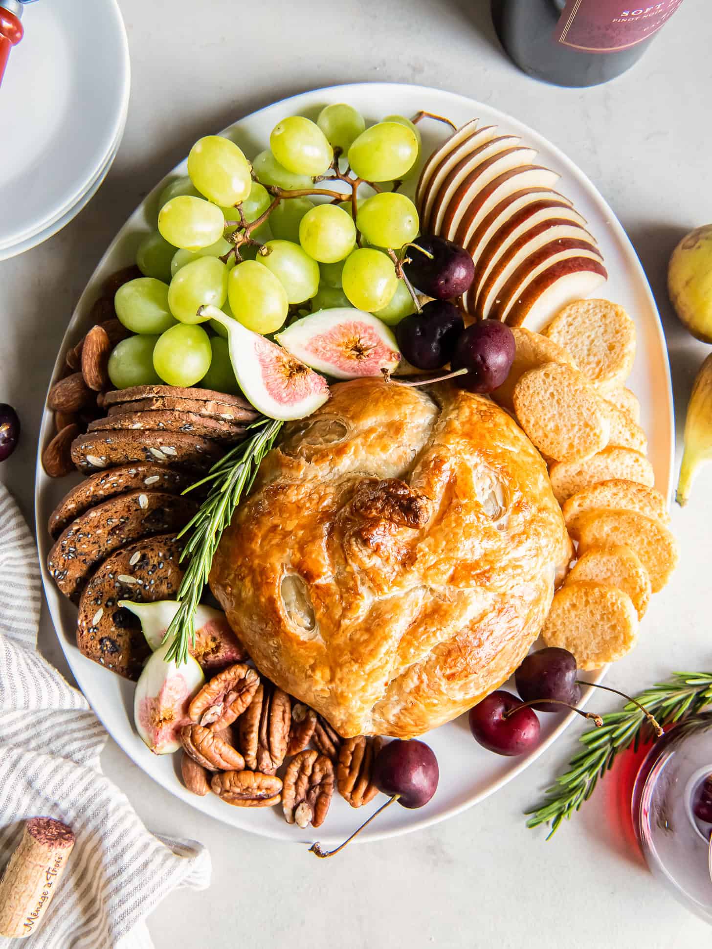 Baked brie on a serving tray with grapes, crackers and figs.