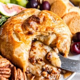 Baked brie in puff pastry with a knife in the cheese.