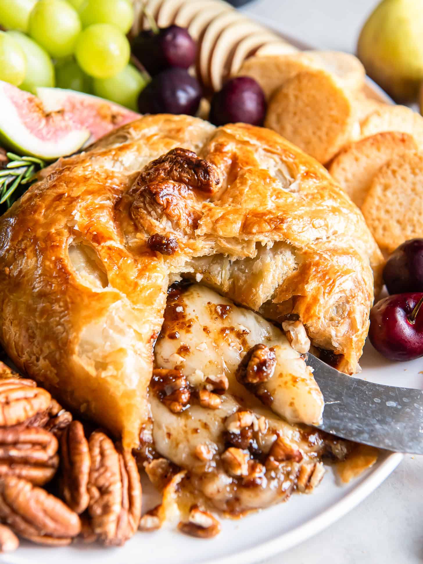 Baked brie in puff pastry with a knife in the cheese.