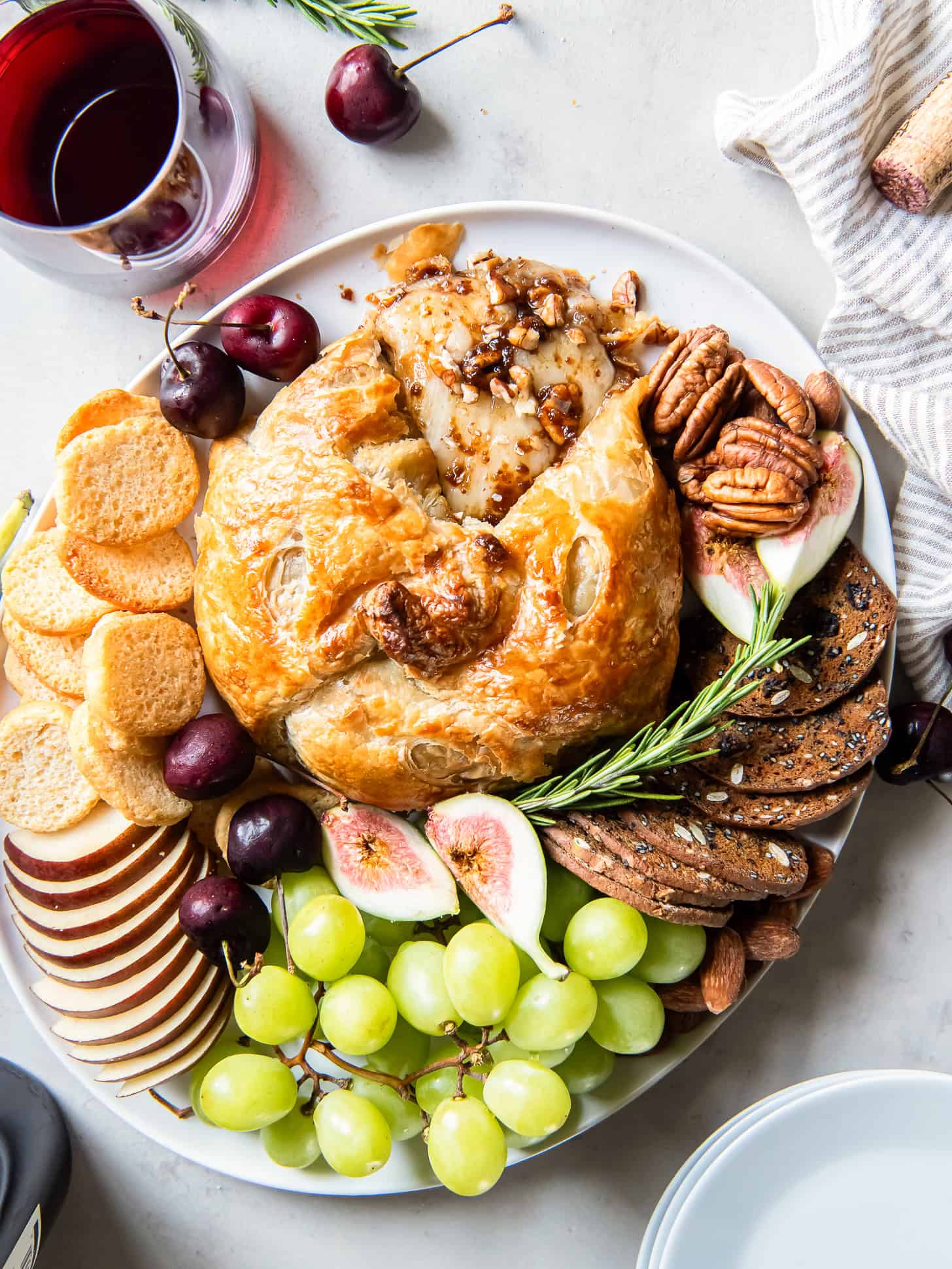 Baked brie on a plate with grapes, crackers and figs.