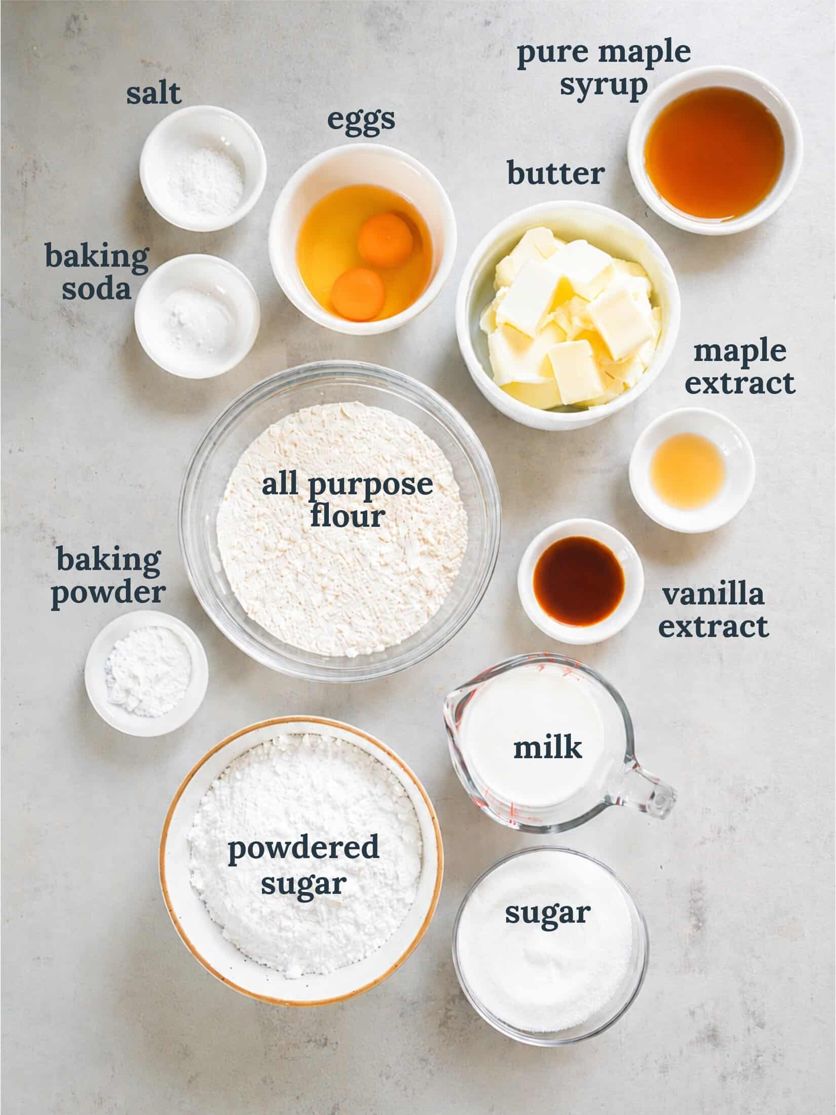 Small bowls with flour, sugar, butter, vanilla, butter and other ingredients for maple cupcakes.