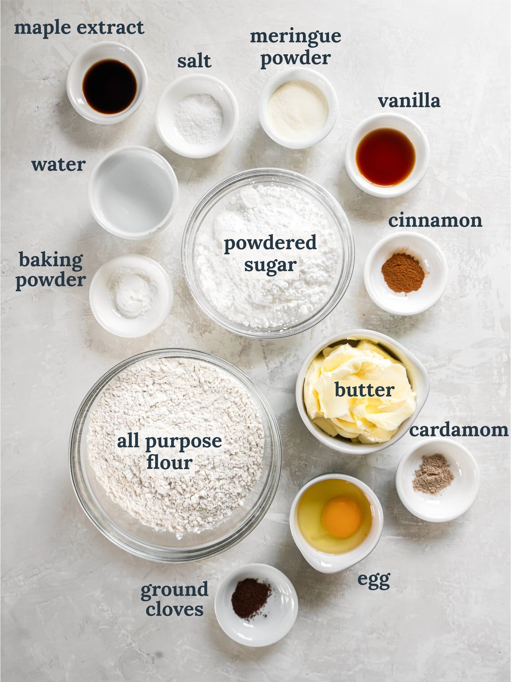 Small bowls with flour, powdered sugar, butter, spices, vanilla and water.